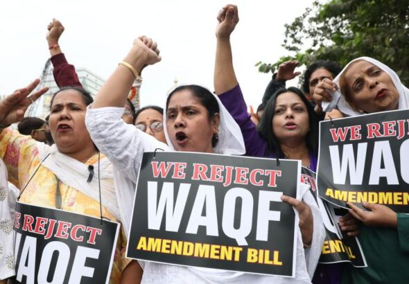 Women holding placards with text we oppose waqf amendment bill written on it.
