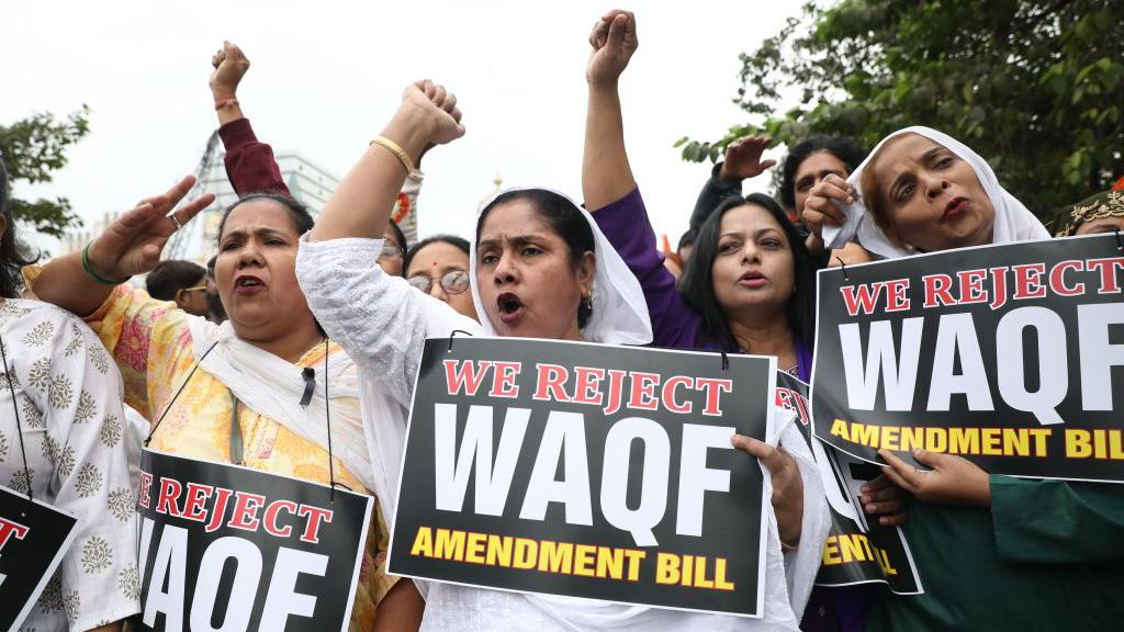 Women holding placards with text we oppose waqf amendment bill written on it.