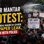 Protesters and police clash near Parliament during the Jantar Mantar protest over the NEET paper leak.Image of a large student protest march in an Indian city street, police barricades, tear gas smoke in the background